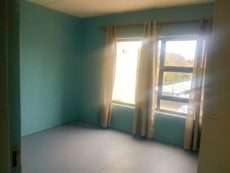 An empty bedroom featuring painted walls and an aluminium window frame, offering a blank canvas for potential interior design updates.