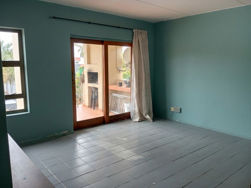 An empty living room featuring tiled flooring and a sliding glass door providing access to an outdoor patio area.