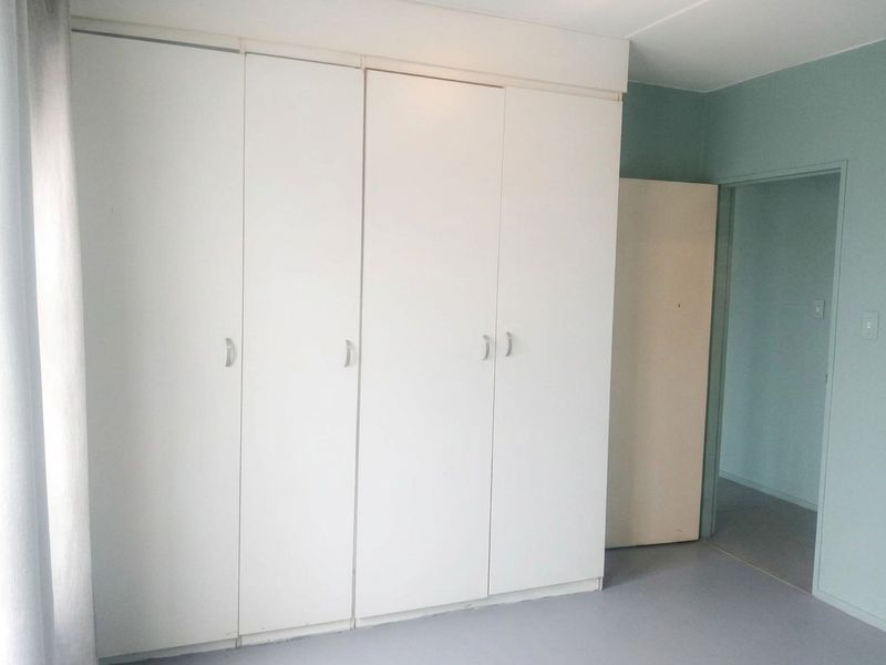 A bedroom featuring floor-to-ceiling built-in cupboards with white doors and a neutral interior finish.