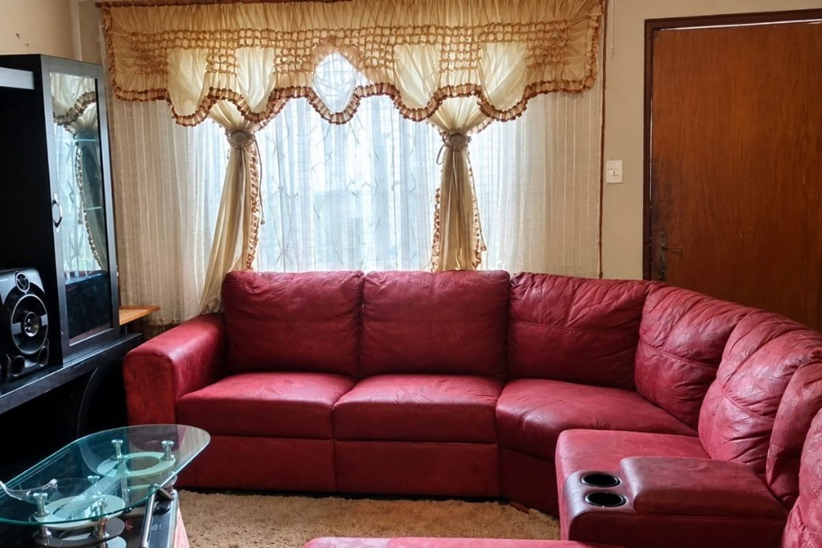 A living room featuring tiled flooring and a timber door, currently showing signs of wear on the wall surfaces.