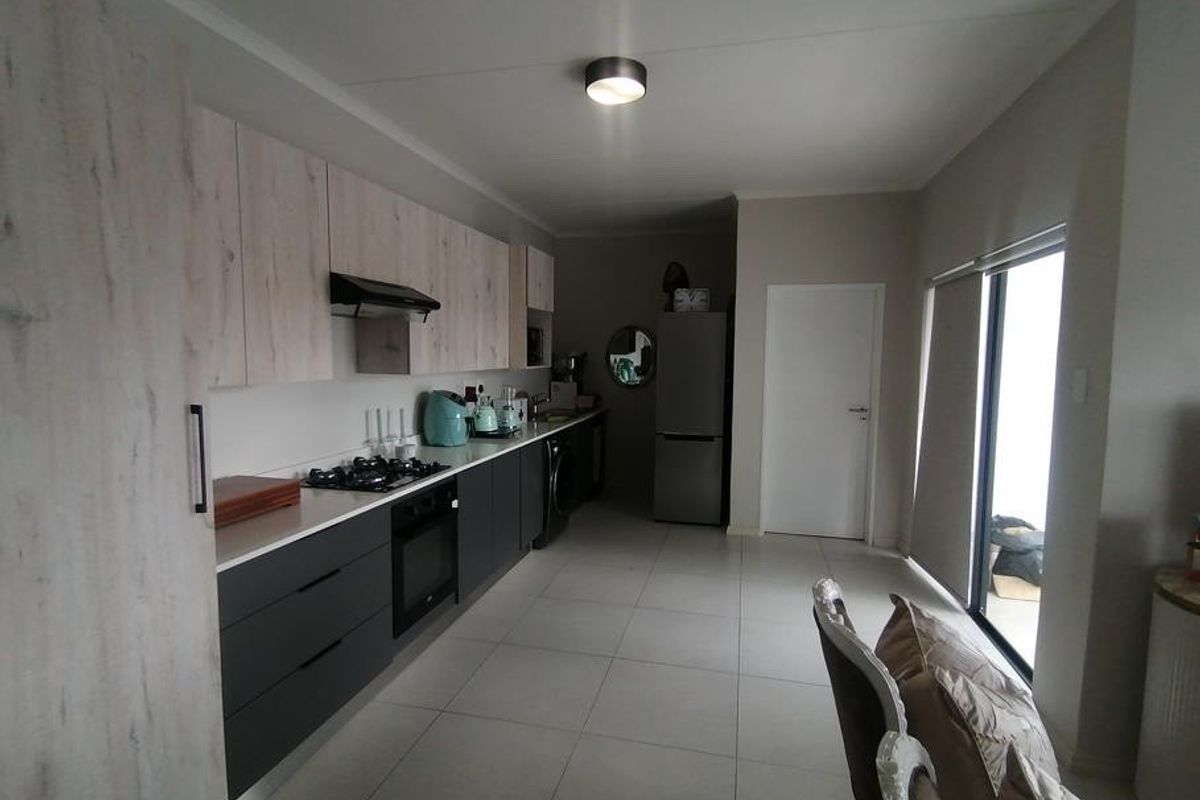 Modern kitchen featuring two-tone cabinetry, gas hob, built-in oven, extractor fan, and tiled flooring with direct access to an outdoor area.