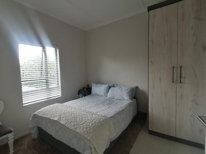A well-lit bedroom featuring a built-in wardrobe and venetian blinds, providing a functional and comfortable living space.