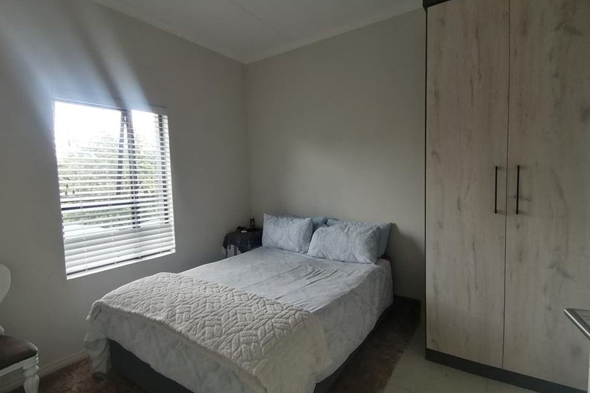 A well-lit bedroom featuring a built-in wardrobe and venetian blinds, providing a functional and comfortable living space.