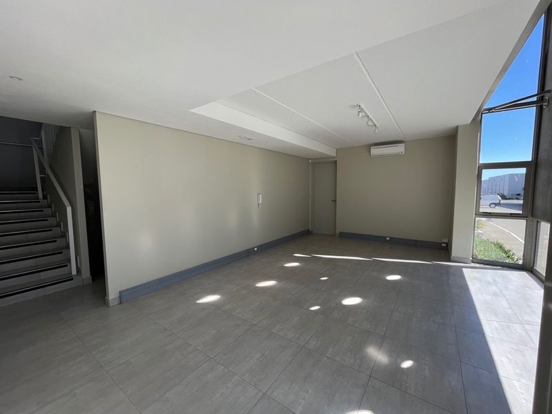 Spacious open-plan industrial office area featuring modern tiled flooring, split-system air conditioning, and large windows providing ample natural light.