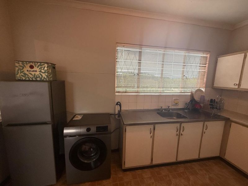 A functional kitchen area featuring built-in cabinetry, a stainless steel sink, and a tiled backsplash, offering potential for modernization and aesthetic updates.