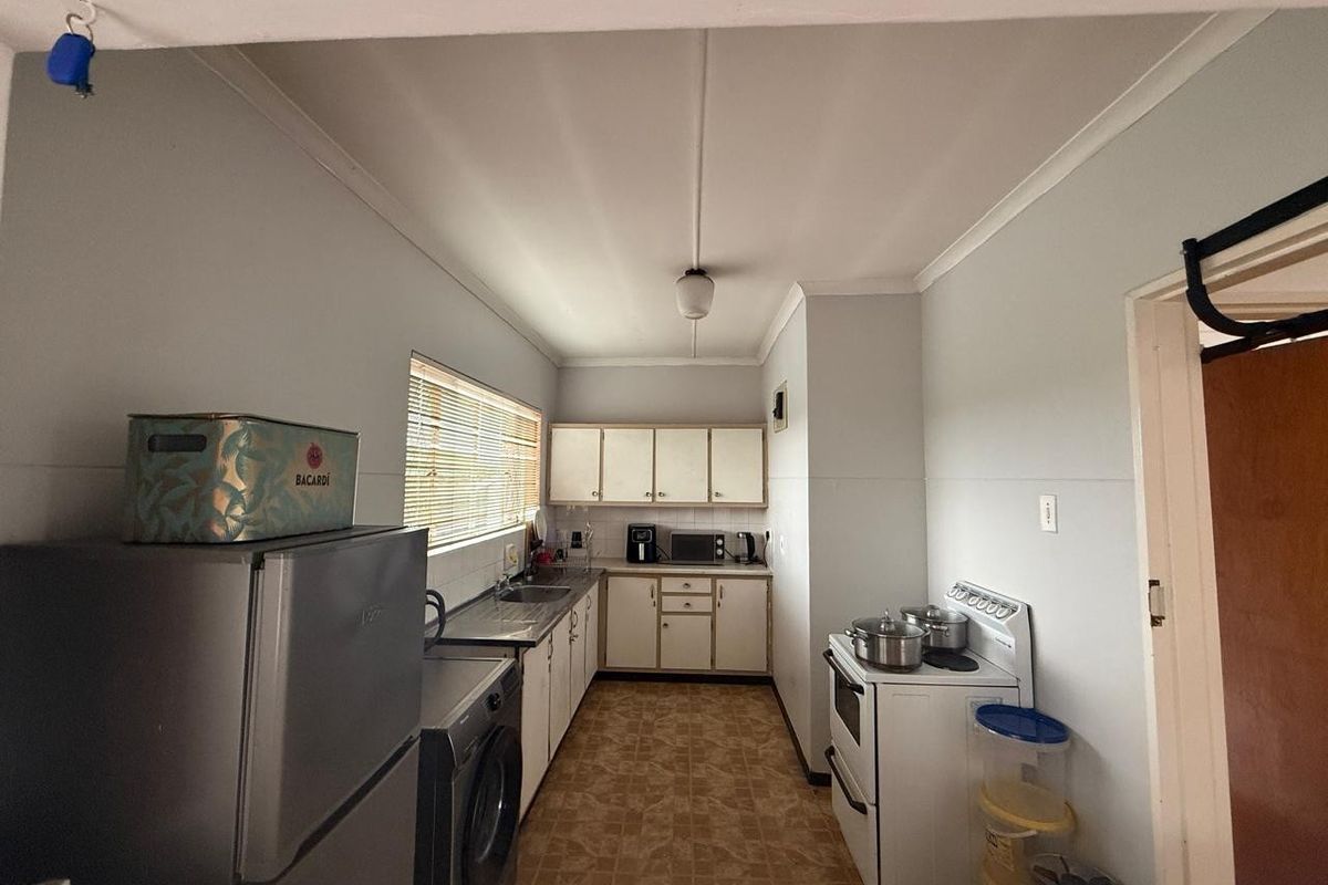 Functional kitchen featuring built-in cabinetry, laminate countertops, a stainless steel sink, and a freestanding stove, with neutral wall finishes.
