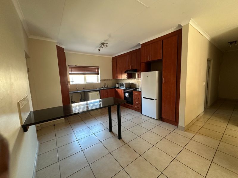 Functional kitchen featuring wooden cabinetry, built-in oven and hob, tiled flooring, and a convenient breakfast bar counter.