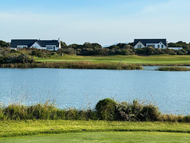 A scenic view overlooking a tranquil lake and manicured golf course fairways with residential properties in the background.