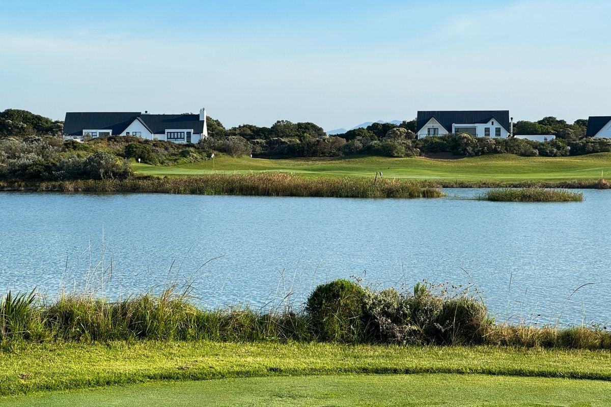A scenic view overlooking a tranquil lake and manicured golf course fairways with residential properties in the background.