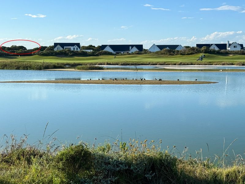 A scenic view overlooking a tranquil water body and golf course landscape, highlighting the natural surroundings of the residential estate.