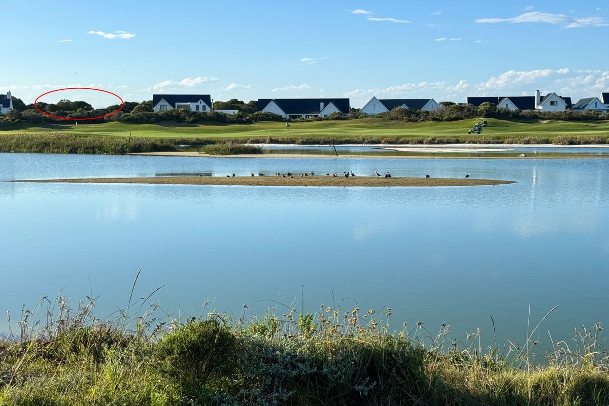 A scenic view overlooking a tranquil water body and golf course landscape, highlighting the natural surroundings of the residential estate.