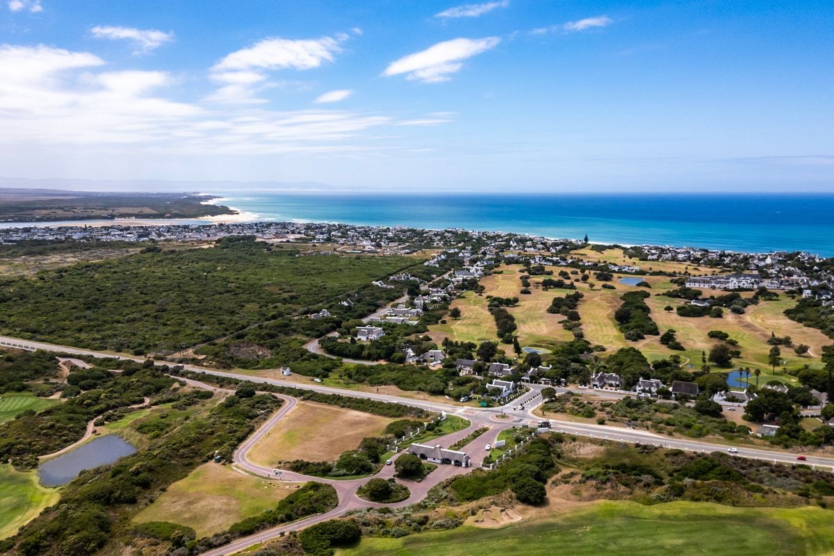 An aerial view of the residential estate, showcasing the gated entrance, surrounding golf course, and proximity to the coastline.