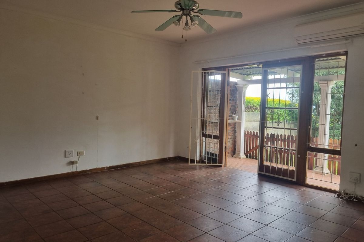 Spacious living area featuring tiled flooring, a ceiling fan, air conditioning, and sliding glass doors providing access to the outdoor patio.