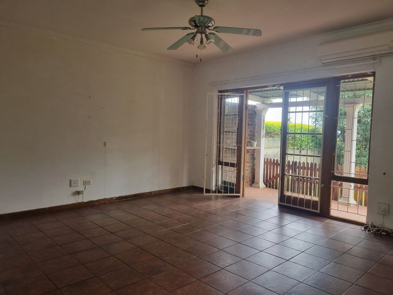 Spacious living area featuring tiled flooring, a ceiling fan, air conditioning, and sliding glass doors providing access to the outdoor patio.
