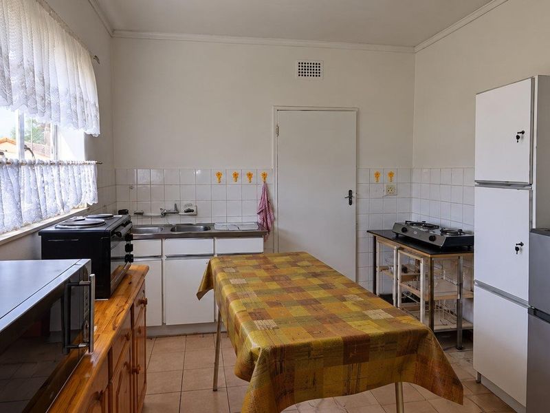 A functional kitchen featuring tiled flooring, a tiled backsplash, and basic cabinetry, offering potential for modernization and renovation.