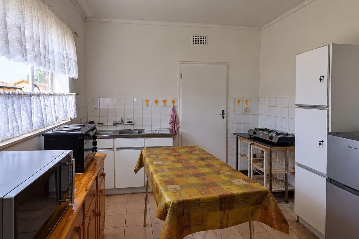 A functional kitchen featuring tiled flooring, a tiled backsplash, and basic cabinetry, offering potential for modernization and renovation.