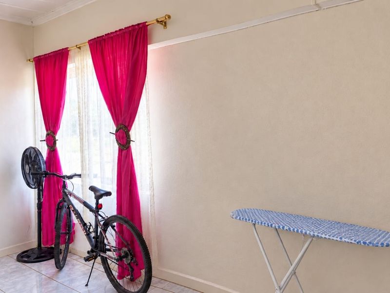 A simple bedroom featuring tiled flooring and a window with curtain rods, providing a neutral base for potential interior design updates.