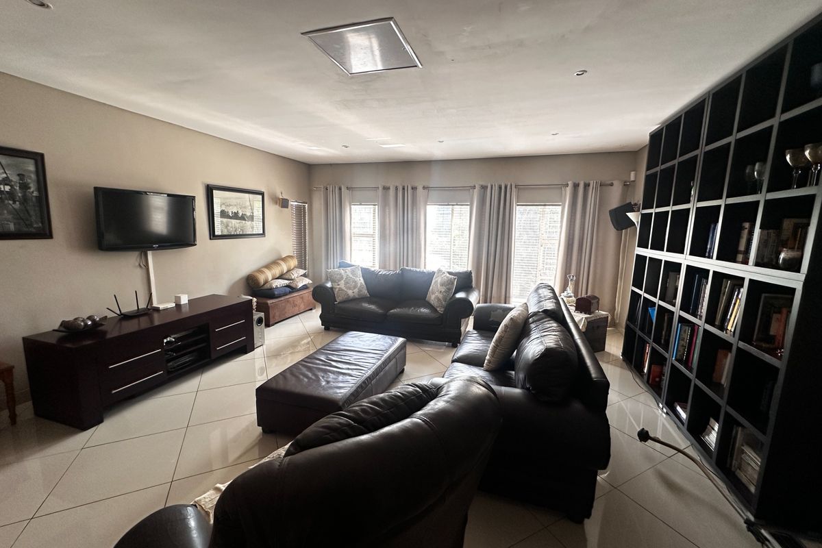 Spacious living room featuring large windows, tiled flooring, recessed lighting, and a large built-in shelving unit.