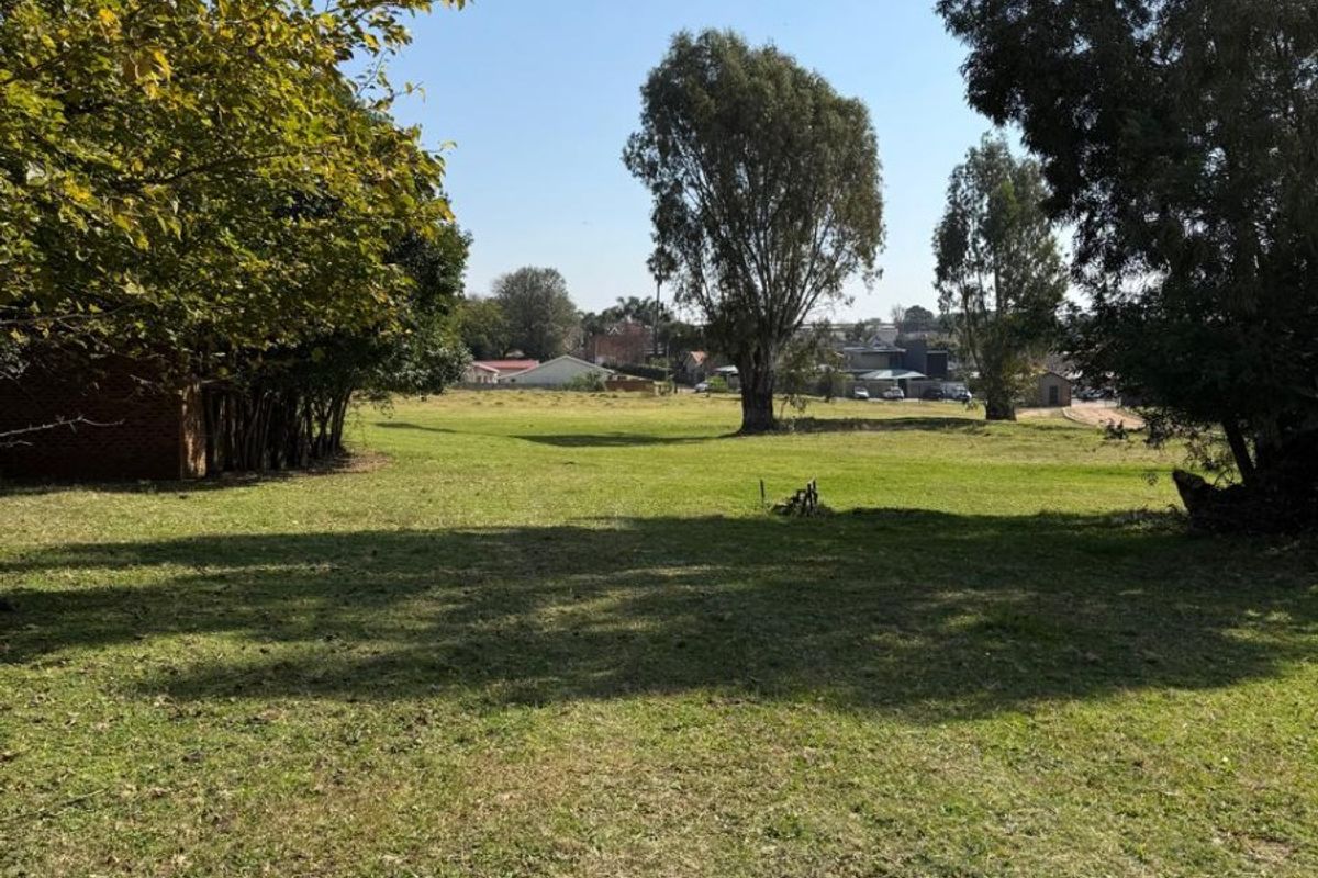 A spacious, open garden area featuring mature trees and well-maintained lawn, offering a peaceful outdoor setting.