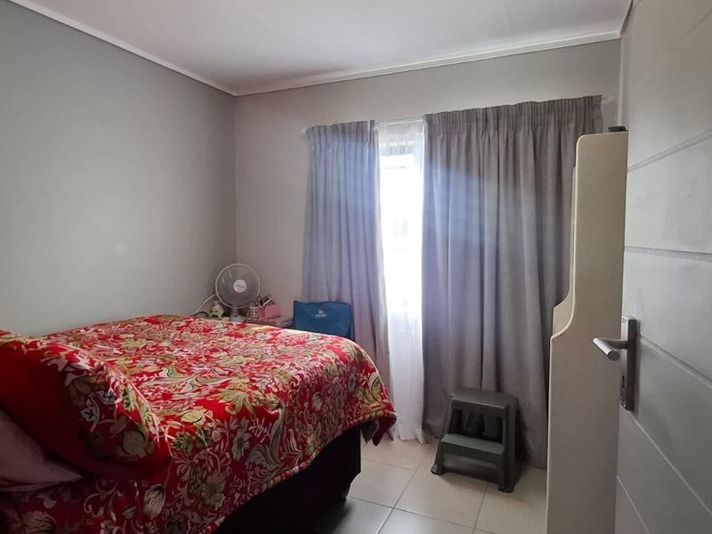 A functional bedroom featuring tiled flooring and neutral wall tones, providing a comfortable and well-lit space.
