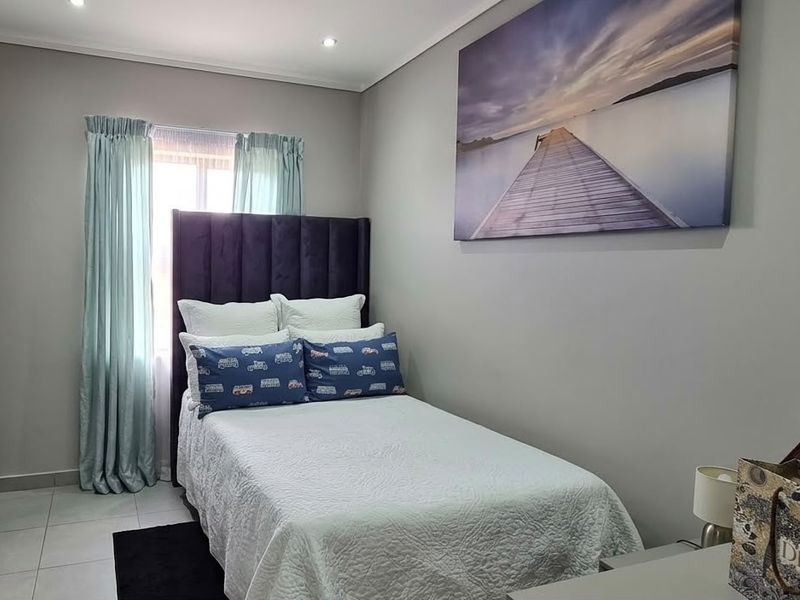 A well-maintained bedroom featuring tiled flooring, recessed downlighting, and a built-in wardrobe, offering a clean and functional living space.
