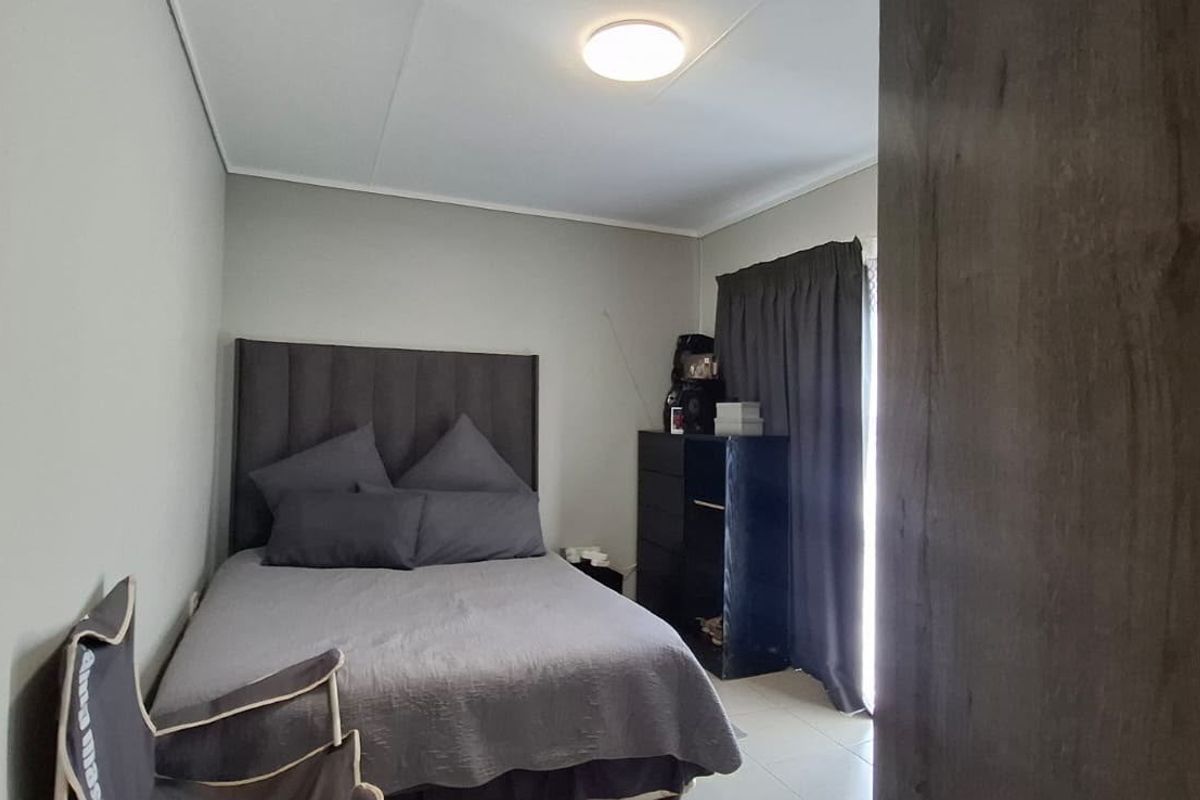 A functional bedroom featuring tiled flooring and neutral wall finishes, providing a simple and practical living space.