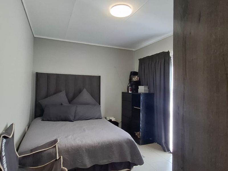 A functional bedroom featuring tiled flooring and neutral wall finishes, providing a simple and practical living space.