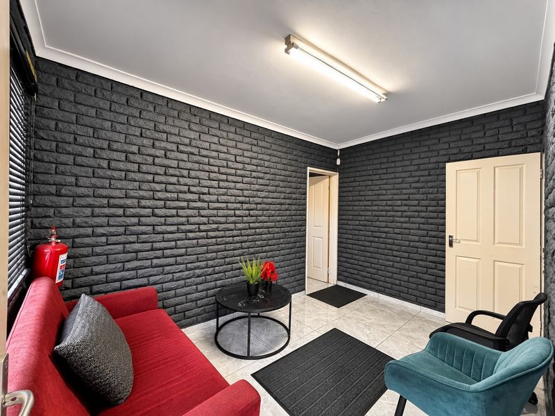 A living area featuring a striking black brick feature wall, tiled flooring, and a functional ceiling light fixture.