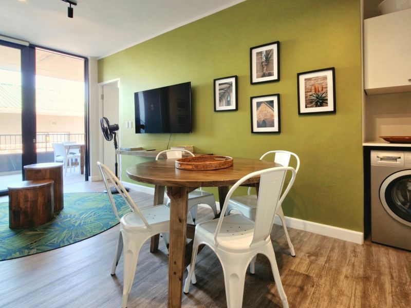 Open-plan living area featuring laminate flooring, a built-in laundry nook with integrated washing machine, and direct access to a private balcony.