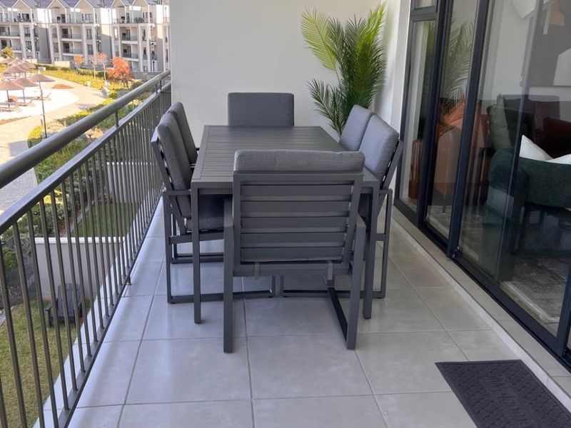 A spacious covered balcony featuring modern light-grey floor tiles, a secure metal balustrade, and large sliding glass doors providing access to the interior.