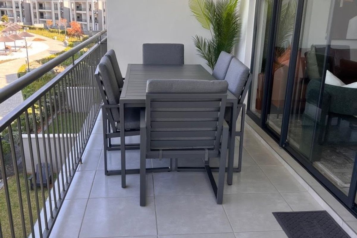 A spacious covered balcony featuring modern light-grey floor tiles, a secure metal balustrade, and large sliding glass doors providing access to the interior.