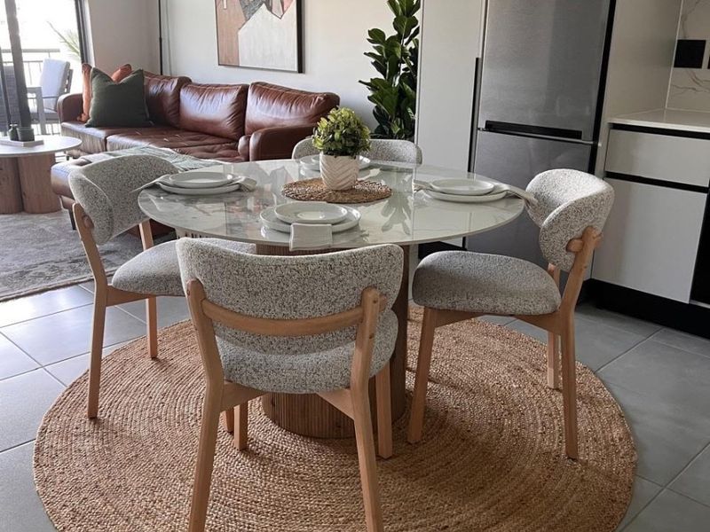 Modern open-plan living and dining area featuring sleek tiled floors, contemporary kitchen cabinetry, and seamless access to an outdoor balcony space.