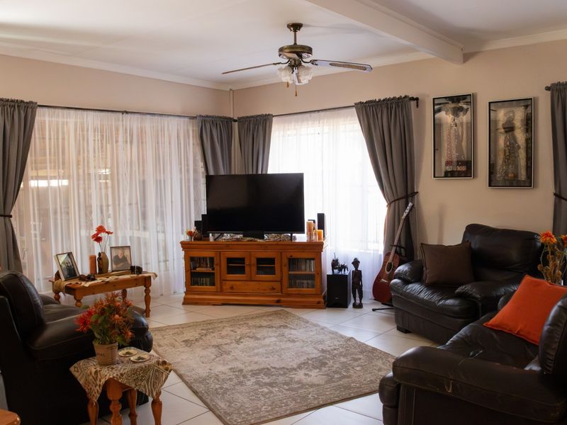 A comfortable living room featuring tiled flooring, a ceiling fan, and large sliding glass doors that provide ample natural light.
