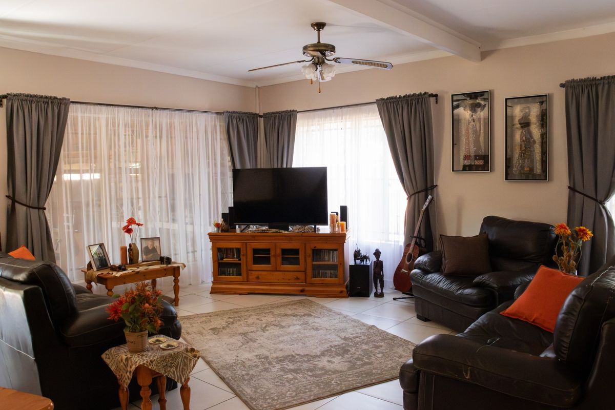 A comfortable living room featuring tiled flooring, a ceiling fan, and large sliding glass doors that provide ample natural light.