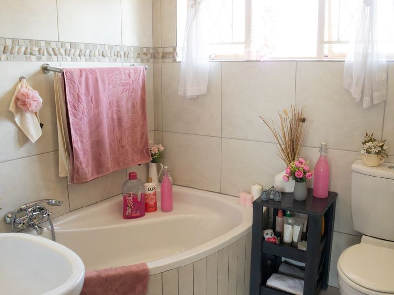 A functional bathroom featuring a corner bathtub, tiled wall finishes, and a standard toilet, offering a clean and practical layout.