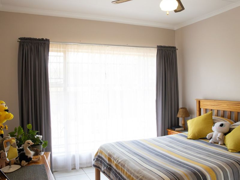 A bedroom featuring tiled flooring, a ceiling fan, and a large window with curtain rod installation.