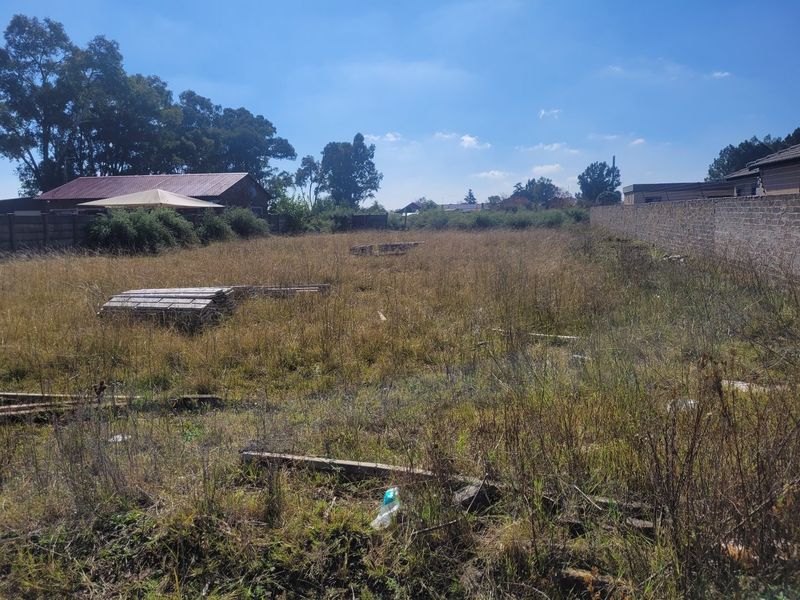 A vacant residential plot featuring overgrown grass and perimeter boundary walls, offering a blank canvas for future development.