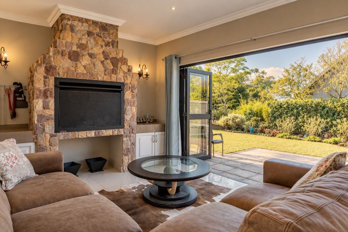 Spacious living room featuring a prominent stone fireplace, built-in cabinetry, and large bi-fold doors opening onto a landscaped garden patio.