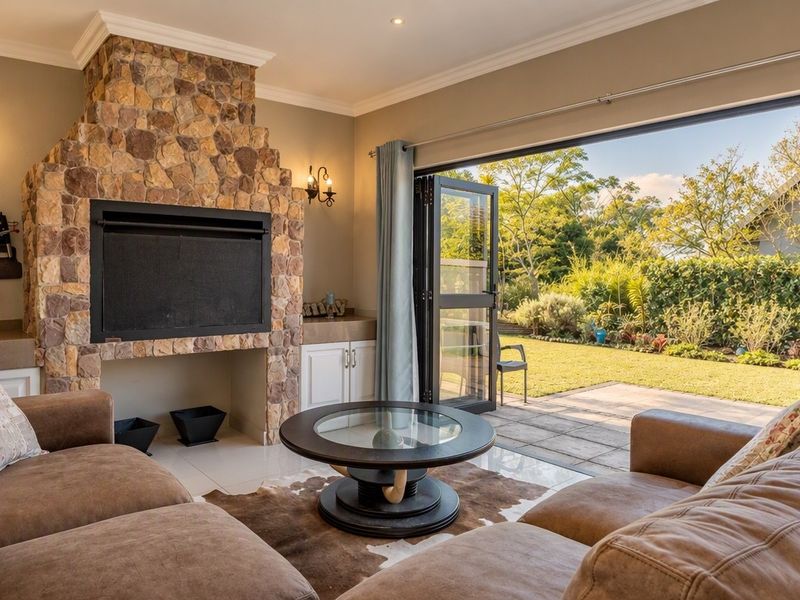 Spacious living room featuring a prominent stone fireplace, built-in cabinetry, and large bi-fold doors opening onto a landscaped garden patio.