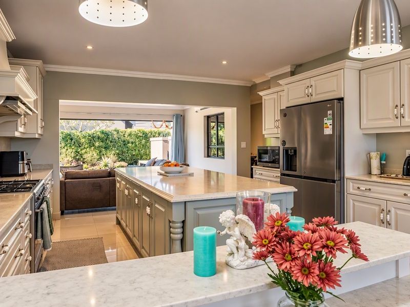 A well-appointed kitchen featuring a large central island, stone countertops, ample cabinetry, and a gas hob, seamlessly flowing into an adjacent living area.