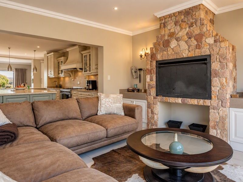 Spacious open-plan living area featuring a prominent stone-clad fireplace, integrated cabinetry, and a seamless transition into a well-appointed kitchen with a central island.