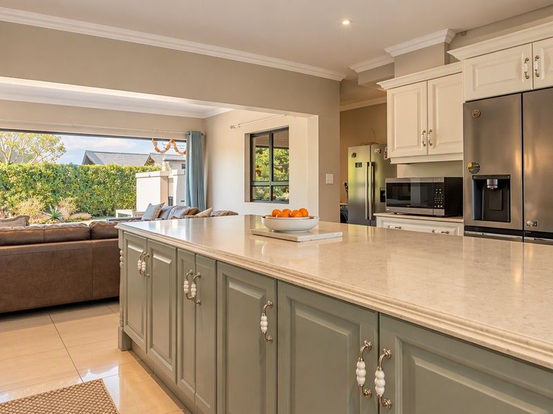 Spacious open-plan kitchen featuring a large central island with stone countertops, shaker-style cabinetry, and seamless flow into the adjacent living area.