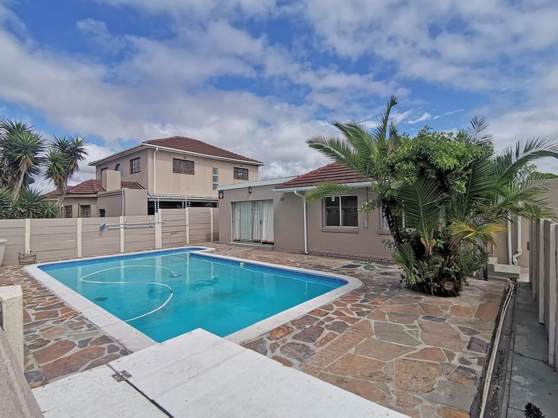 Outdoor pool area featuring a swimming pool, crazy paving stone patio, and precast concrete boundary walls, set against a residential building exterior.