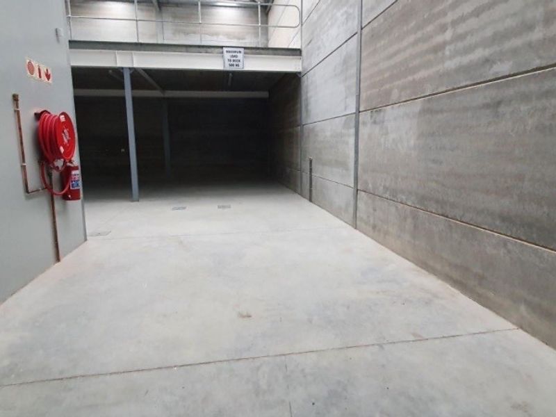 Spacious industrial utility area featuring durable concrete flooring, precast wall panels, and a mezzanine level with integrated fire safety equipment.