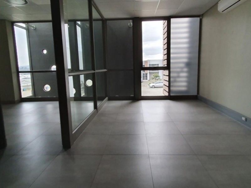 Modern, empty office space featuring large glass partitions, tiled flooring, and an integrated air conditioning unit, offering a clean and professional industrial workspace.