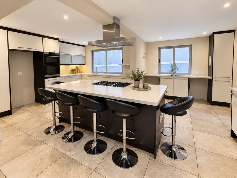 Modern kitchen featuring a large central island with gas hob, stone countertops, built-in oven, and ample cabinetry with recessed lighting.