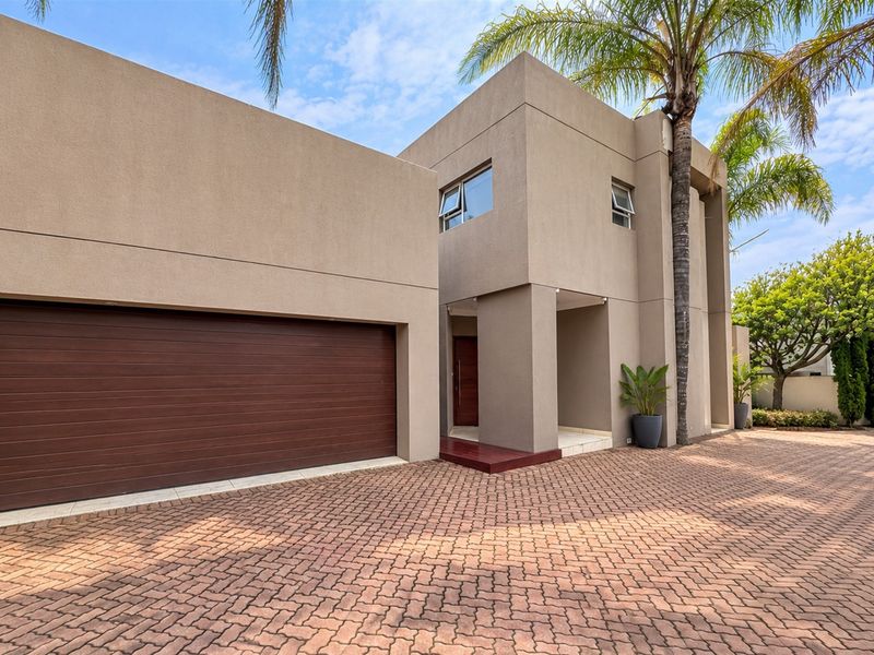 Modern double-story residence featuring a clean stucco facade, a spacious paved driveway, and an integrated double garage.