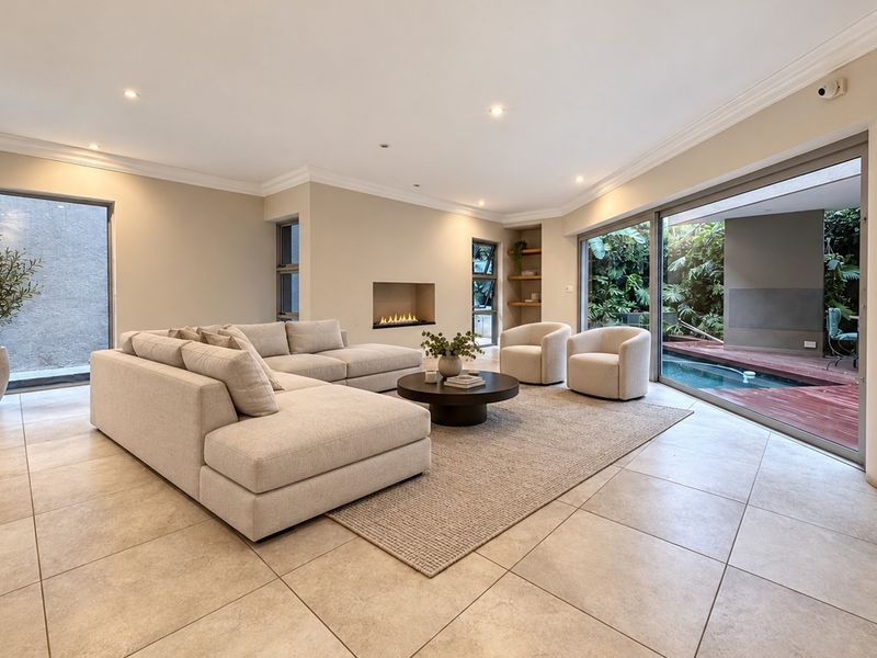 Spacious living room featuring large sliding glass doors opening to a pool area, recessed fireplace, and modern tiled flooring.