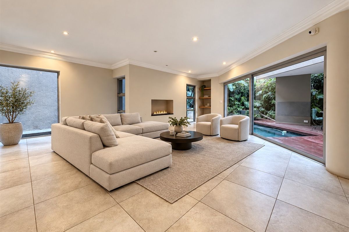 Spacious living room featuring large sliding glass doors opening to a pool area, recessed fireplace, and modern tiled flooring.