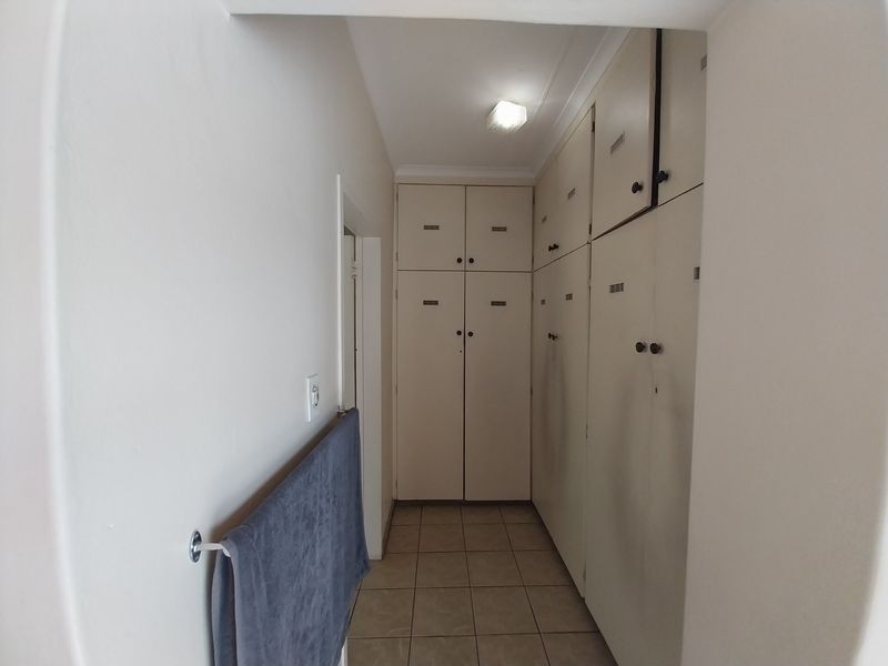 A functional hallway featuring extensive built-in floor-to-ceiling storage cabinetry and tiled flooring, providing ample storage space.
